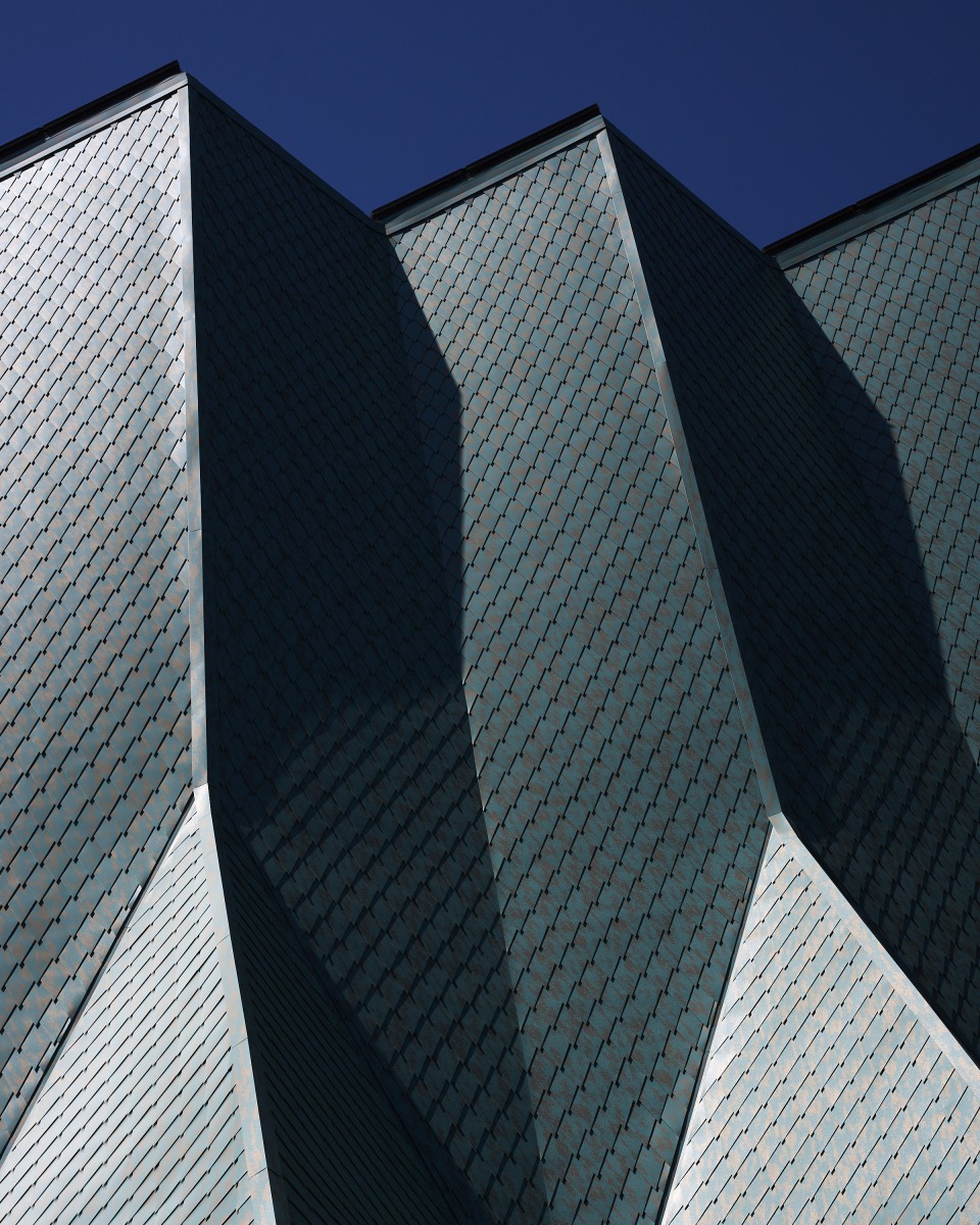 20260425_Metis_StPaul_4240 Close-up of angular metal roof panels on a building against a clear blue sky.